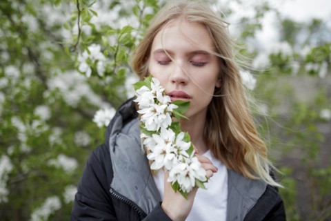 Young woman with her eyes closed holding white blossoms