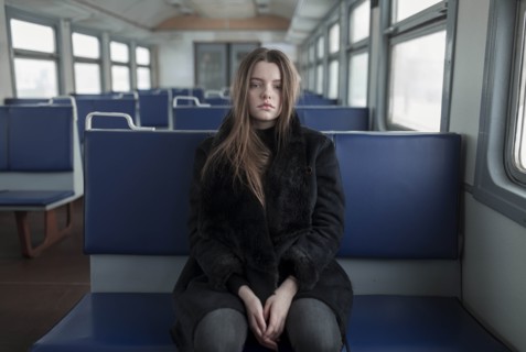 Young woman wearing black fur coat on train