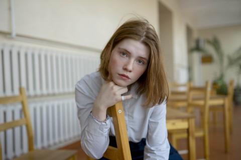 Young woman leaning on wooden chair