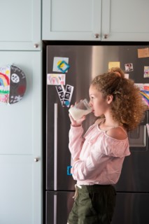 Girl drinking glass of milk in kitchen