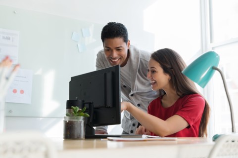 Coworkers smiling at computer together