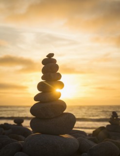 Stacked stones on beach at sunset