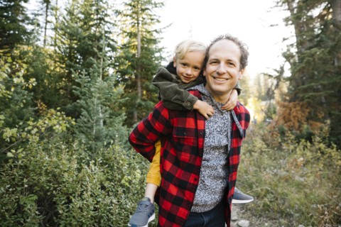 Father and son piggyback in forest