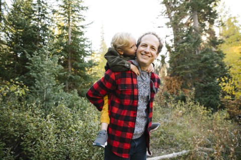 Father and son piggyback in forest