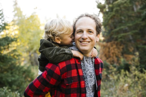 Father and son piggyback in forest