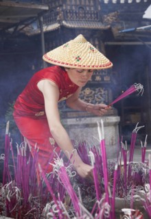 Woman lighting incense in temple in Lijang, Shangri-La Region, Yunnan Province, China