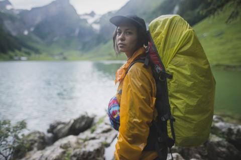 Woman wearing yellow backpack by Seealpsee lake in Appenzell Alps, Switzerland
