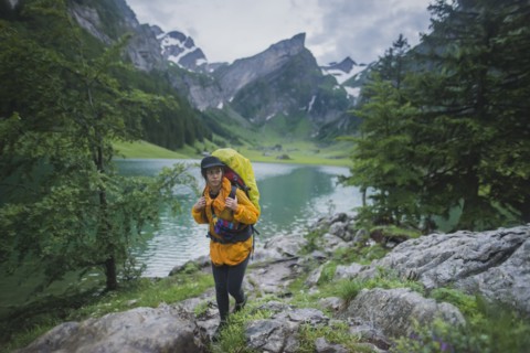 Woman wearing yellow hiking by Seealpsee lake in Appenzell Alps, Switzerland