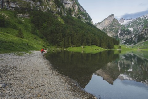 Woman crouching by Seealpsee lake in Appenzell Alps, Switzerland