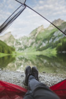 Woman's feet sticking out of tent by Seealpsee lake in Appenzell Alps, Switzerland