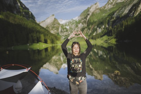 Woman making heart hand sign by Seealpsee lake in Appenzell Alps, Switzerland