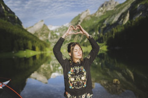 Woman making heart hand sign by Seealpsee lake in Appenzell Alps, Switzerland