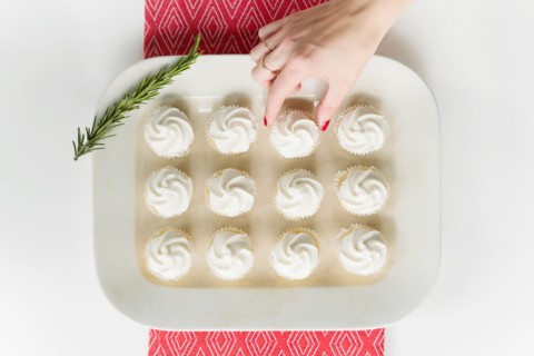Woman's hand reaching for cupcake on tray