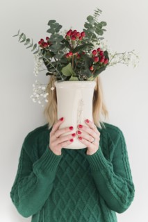Woman wearing green holding vase of flowers