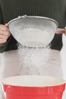 Woman sifting flour into bowl