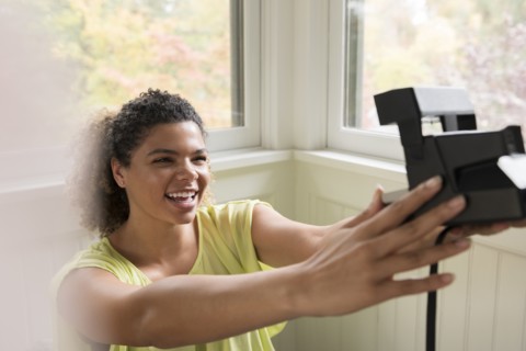Smiling woman taking selfie with Polaroid camera