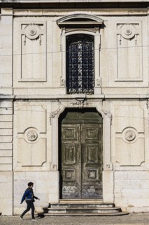Woman walking past old building in Lisbon, Portugal