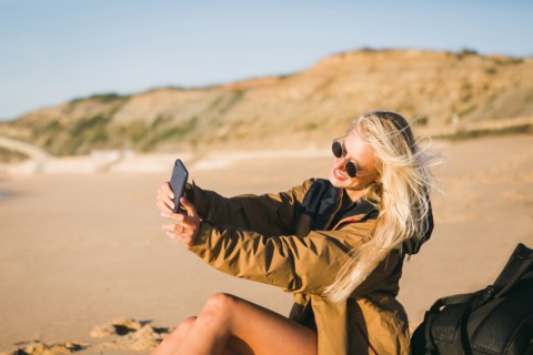 Smiling woman taking selfie on beach