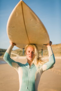 Woman holding surfboard above her head at beach