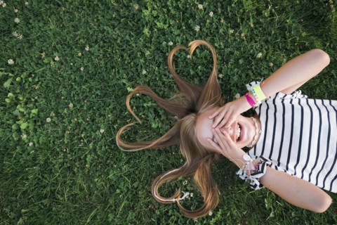 Girl with her hair in heart shapes lying on grass