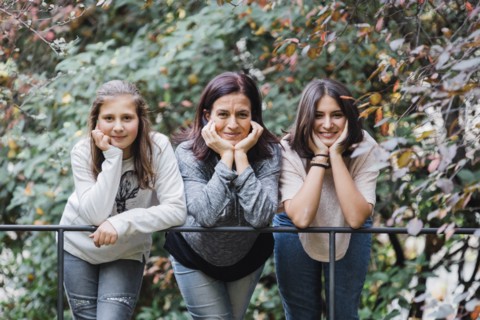 Mother and daughters smiling and  leaning on railing