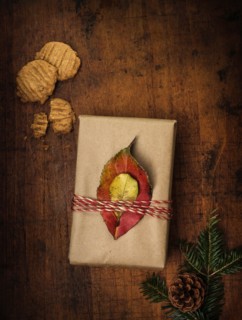 Leaves tied to Christmas present next to cookies