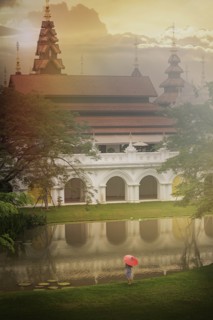 Woman holding umbrella by temple in Chiang Mai, Thailand