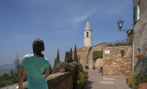 Woman by stone wall and church in Tuscany, Italy