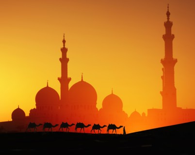 Man with camels in front of Sheikh Zayed Mosque at sunset in Abu Dhabi, United Arab Emirates