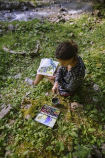 Woman painting with watercolors by river in Appenzell, Switzerland