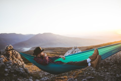 Man lying on hammock in mountain range
