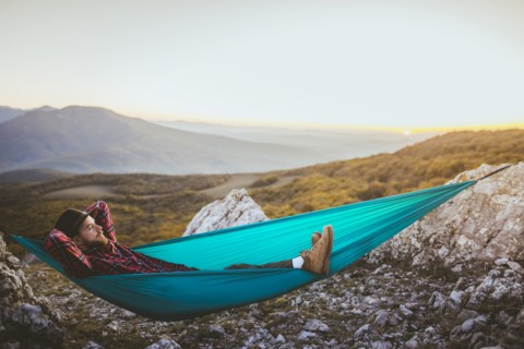 Man lying on hammock in mountain range