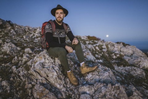 Man sitting on rock at sunset
