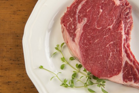 Raw steak and oregano on plate