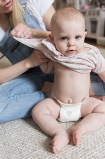 Baby girl being dressed by her mother