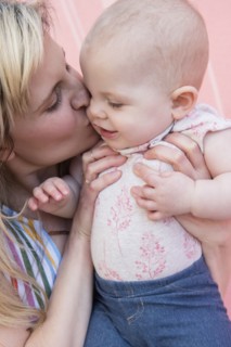Baby girl being kissed by her mother