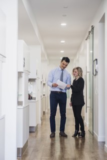 Dentist and dental nurse discussing notes in corridor