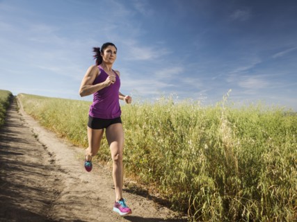 Mid adult woman jogging on path through field