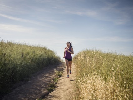 Mid adult woman jogging on path through field