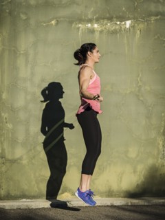 Woman skipping by concrete wall