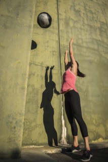 Woman throwing medicine ball against concrete wall