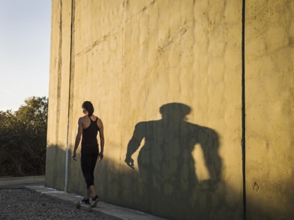 Woman in sportswear walking by concrete wall