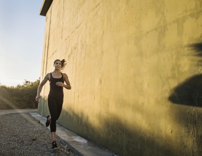 Woman in sportswear jogging by concrete wall