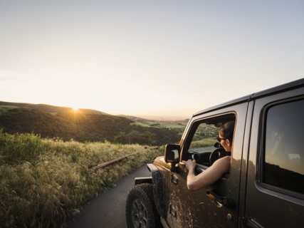 Woman in off road vehicle looking at sunset