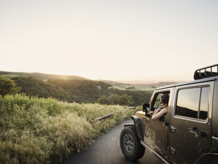 Woman in off road vehicle looking at sunset