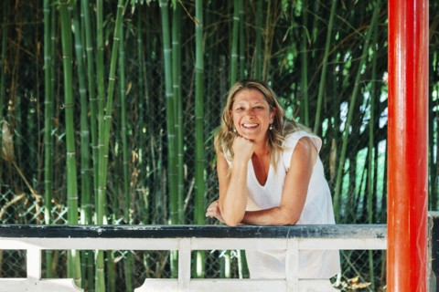 Smiling woman leaning on fence by bamboo