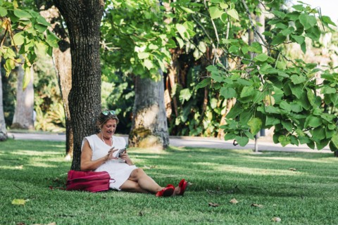 Woman using smart phone under tree