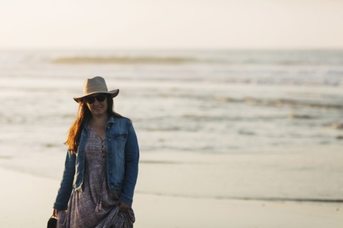 Woman in sunhat and denim jacket on beach