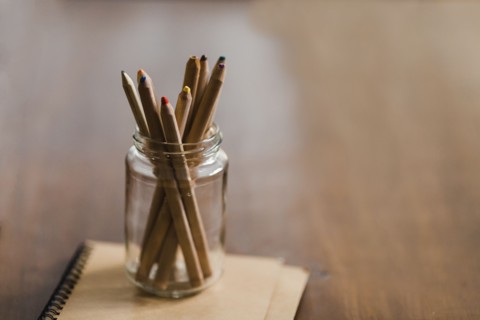 Coloured pencils in jar on book