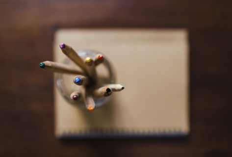Coloured pencils in jar on book